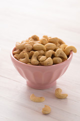 Whole cashews in a pastel bowl on white
