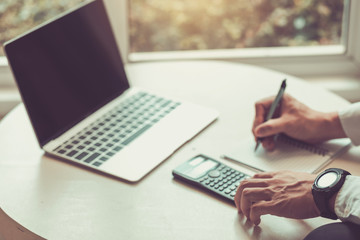 Man using calculator and writing make note with calculate about cost.