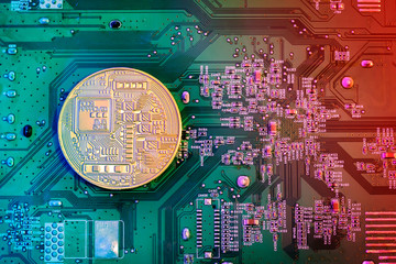 Concept of Bitcoin Mining. Golden Bitcoin on the microchip board close up.