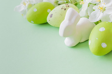 Composition with white spring flowers and easter eggs on a green background