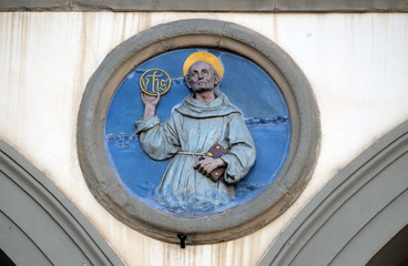St. Bernardino of Siena, glazed terracotta tondo by Andrea della Robbia, located between two arches...