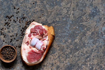 Fresh, raw pork steak with bacon and spices on the kitchen stone table. View from above.
