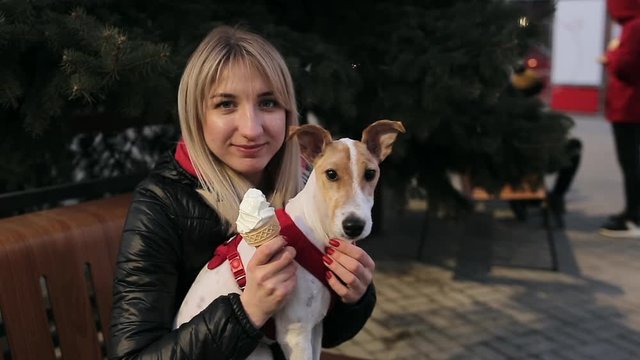 Slow-Motion. Cheerful girl with icecream sitting with her dog on the bench and posing. woman is caressing a dog