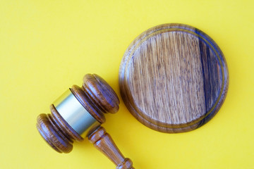 Wooden hammer of the judge on a yellow background, copy-space.