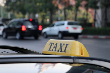 Taxi light sign or cab sign in yellow color with black text on the car roof at the street blurred...