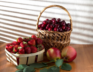 Berries of ripe, red cherries and strawberries under the rays of sunlight.