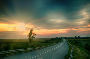 Sunset above the plain, cloudy sky through which the rays break through