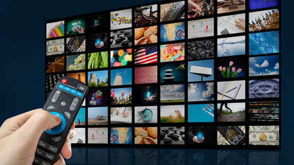 TV screen with lot of pictures and hands of man with remote control.