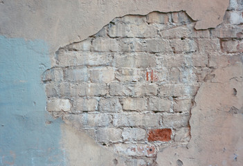 Abandoned old brick wall of the building with painted and crumbling cladding