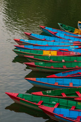 Fototapeta na wymiar Traditional colored wooden rowing boats in Pokhara, Nepal an early morning before they go out onto the lake. Classic view in Pokhara. 