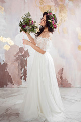 Elegant brunette girl bride with flowers. Beautiful young bride in a lush wedding wreath of fresh flowers