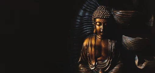 Fotobehang Gouden Gautama Boeddhabeeld met een zwarte achtergrond. © Abhishek