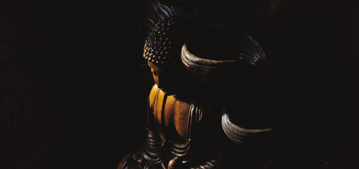 Golden Gautama Buddha statue with a black background.