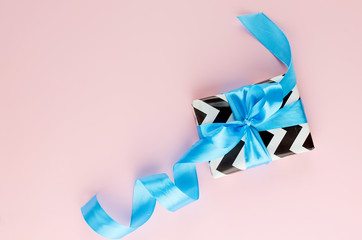 gift with blue ribbon on a pink background