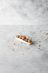 Raw bliss balls with chopped hazelnuts in an oval bowl on textured background