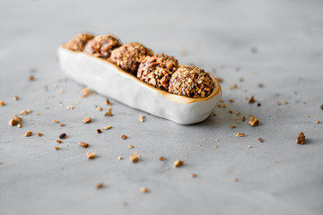 Raw bliss balls with chopped hazelnuts in an oval bowl on textured background