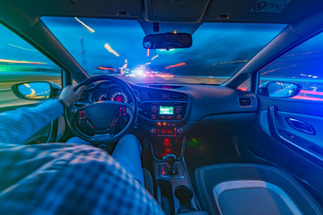 driving a car at night at high speed view from the car. blurred city. one hand driving