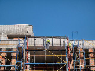 few man workers on scaffolding at construction site of modern office building, store, shopping mall...