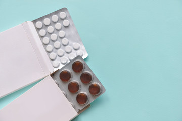 pills medication pills in white paper boxes on an isolated blue background. Doctors and...