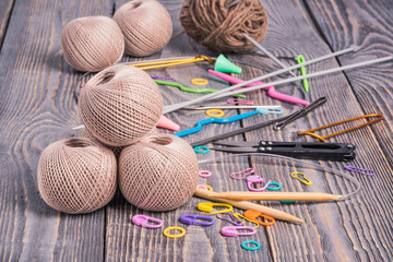Clews of yarn, knitting needles, scissors and clips on wooden background.