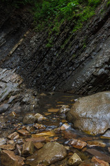 StoneAt the foot of the waterfall. Mountain river on the background of rock and plantss at the foot of the waterfall