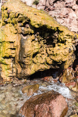 on the shore of the sea is a rock over which the running water has been colored in yellow; next to the red rocks