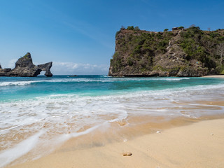 Fototapeta na wymiar The Atuh beach, Nusa Penida island near Bali, Indonesia. Ocean waves, cliffs and a desert beach with tropical plants. October, 2018