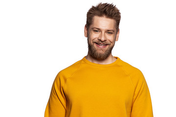 Fototapeta premium Cute guy in a stylish bright sweatshirt stands on an isolated white background and smiling looks at the camera