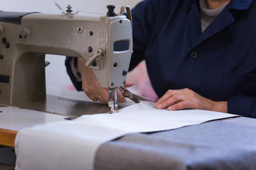 Closeup of an older woman in a furniture factory who is sewing the material for the sofa