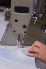 Closeup of an older woman in a furniture factory who is sewing the material for the sofa