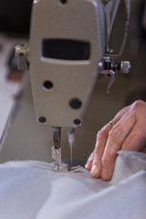 Closeup of an older woman in a furniture factory who is sewing the material for the sofa