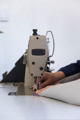 Closeup of an older woman in a furniture factory who is sewing the material for the sofa