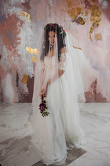 Beautiful young bride in wedding dress with veil on her face