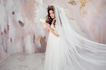 Elegant brunette girl bride with flowers. Beautiful young bride in a lush wedding wreath of fresh flowers