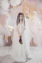 Beautiful young bride in wedding dress with veil on her face