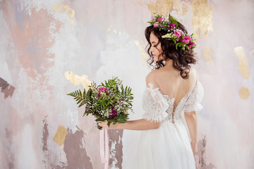 Elegant brunette girl bride with flowers. Beautiful young bride in a lush wedding wreath of fresh flowers