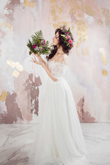 Elegant brunette girl bride with flowers. Beautiful young bride in a lush wedding wreath of fresh flowers