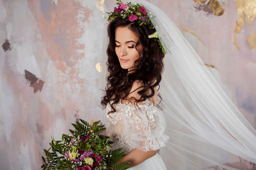 Elegant brunette girl bride with flowers. Beautiful young bride in a lush wedding wreath of fresh flowers