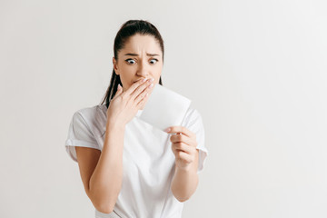 Young woman with a surprised unhappy expression lost a bet on studio background. Human facial emotions and betting concept. Trendy colors.