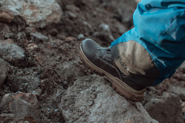 Children's hike in the mountains. Child's foot on the stone.