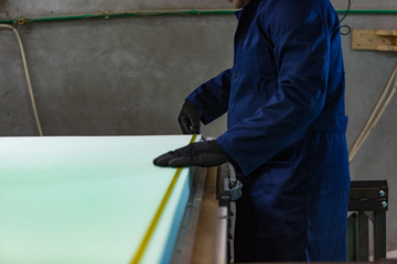 Young man in a furniture factory is measuring the foam for the sofa.