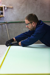 Young man in a furniture factory is measuring the foam for the sofa.