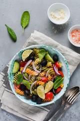 Pasta salad with colorful fusilli and vegetables in a ceramic plate. Top view.