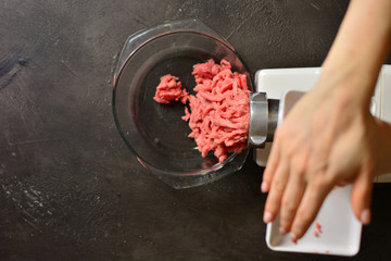 Female hands making minced beef meat with meat grinder