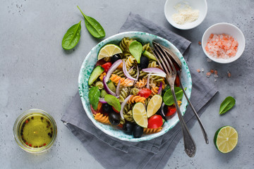Pasta salad with colorful fusilli and vegetables in a ceramic plate. Top view.