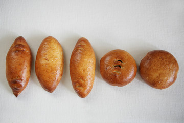 Russian traditional pies with filling laid out in a line on a white background