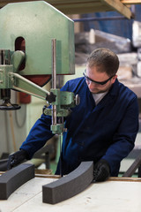 Portrait of a young man in a furniture factory cutting the foam for the sofa