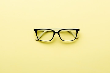 Modern spectacles eye glass isolated on yellow background. Top view.