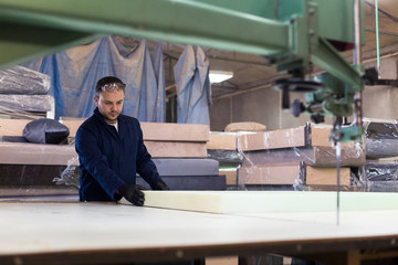 Young man in a furniture factory is measuring the foam for the sofa.