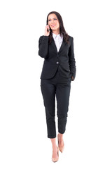 Obraz premium Happy confident business woman walking and talking on the cellphone looking away. Full body isolated on white background.